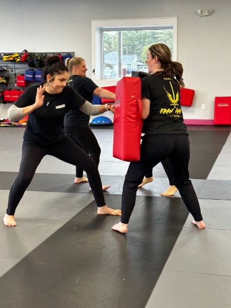 Women practicing defensive striking with a training shield